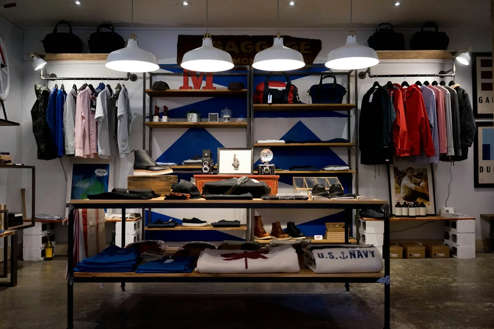 Folded clothing and rails on open shelving in a small boutique