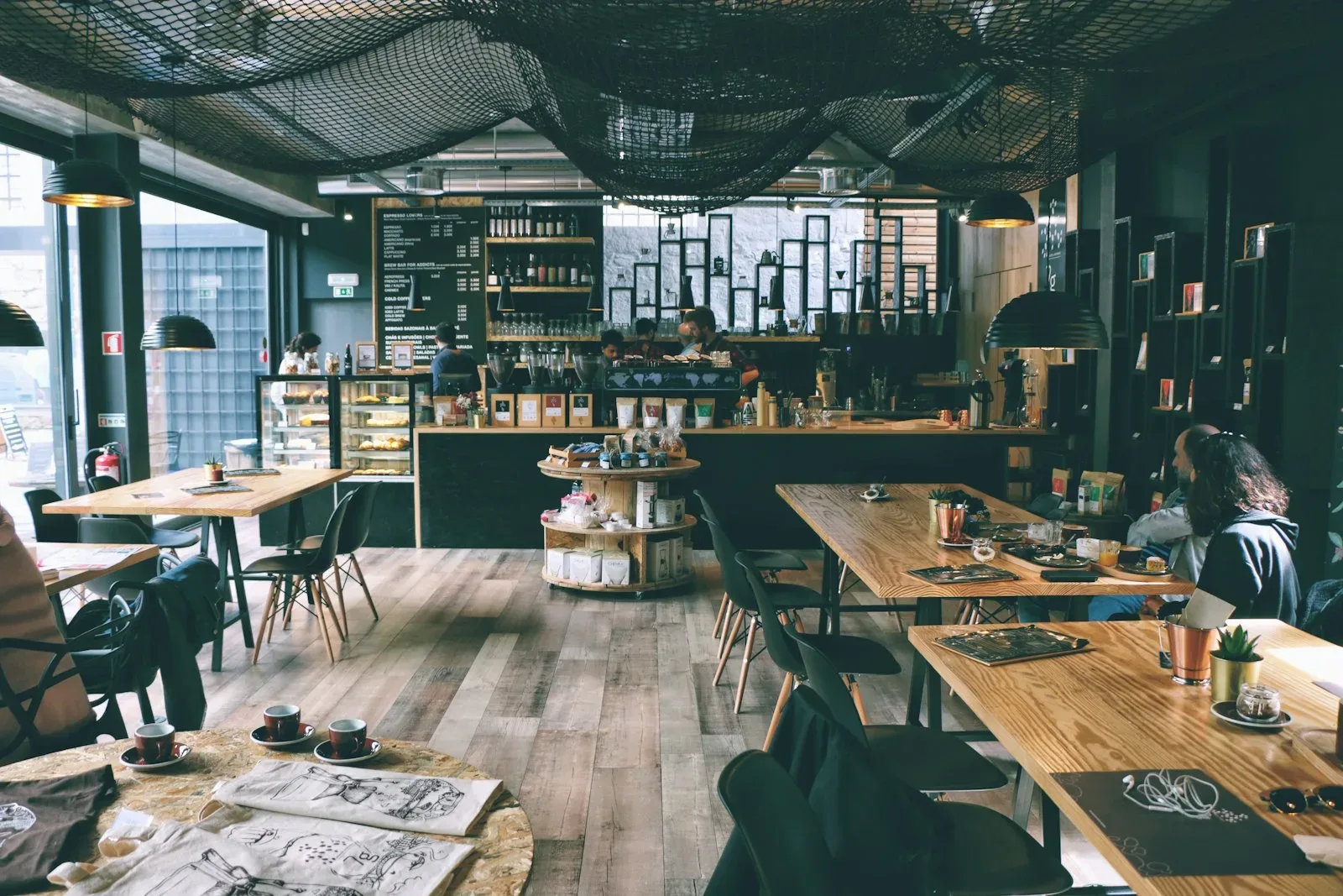 A quiet café interior with long wooden tables under pendant lights