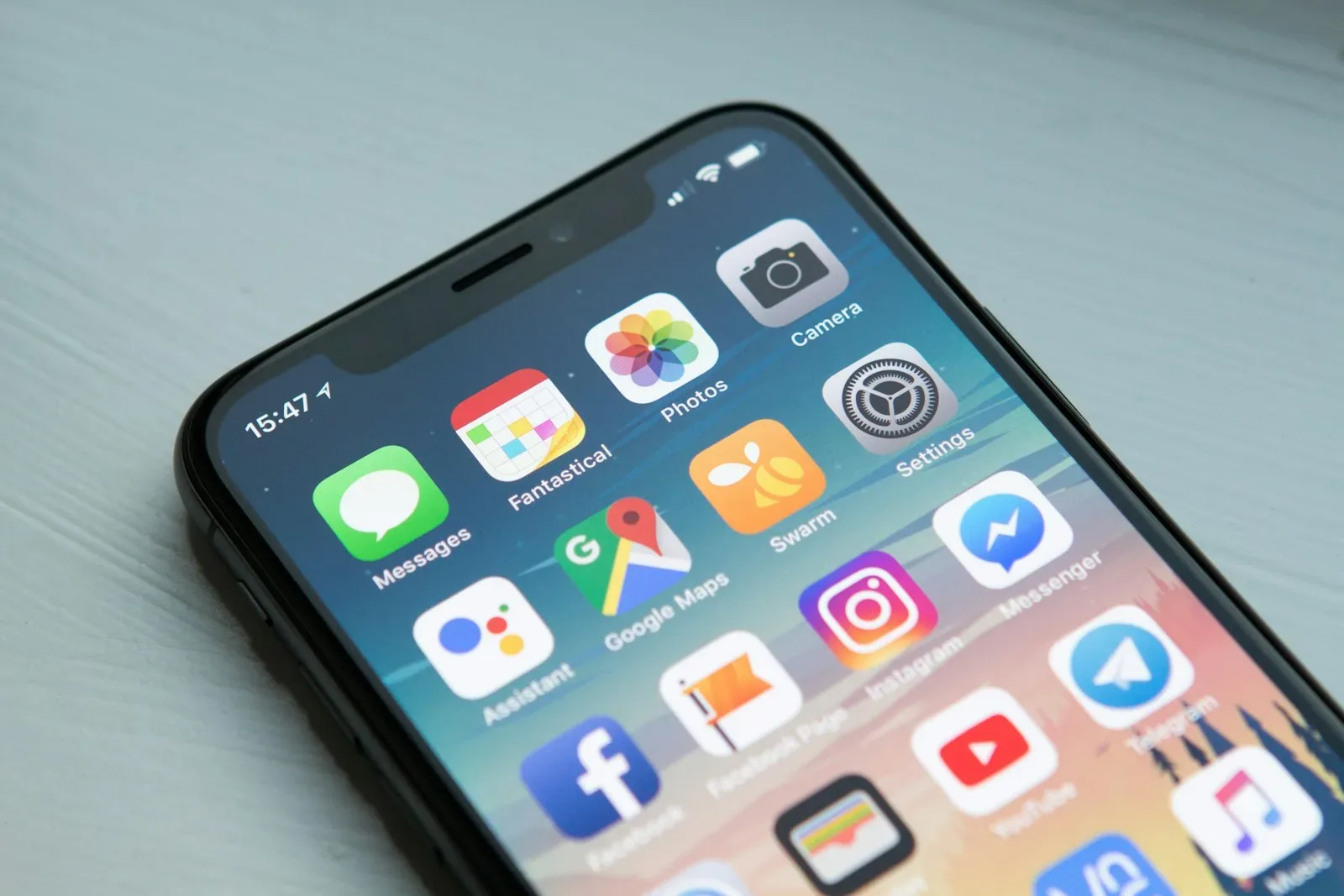 A phone lying on a desk with its home screen lit