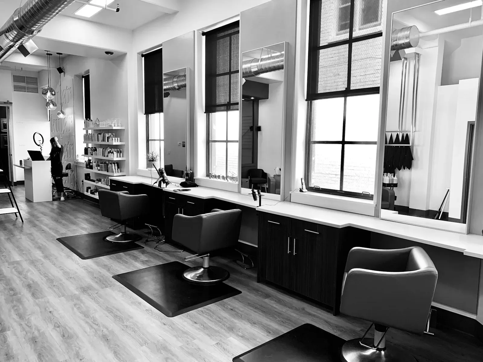 Empty styling chairs facing a mirror wall in a bright hair salon