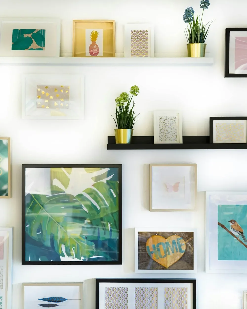 A wall of framed prints and small shelves of plants in a homeware shop