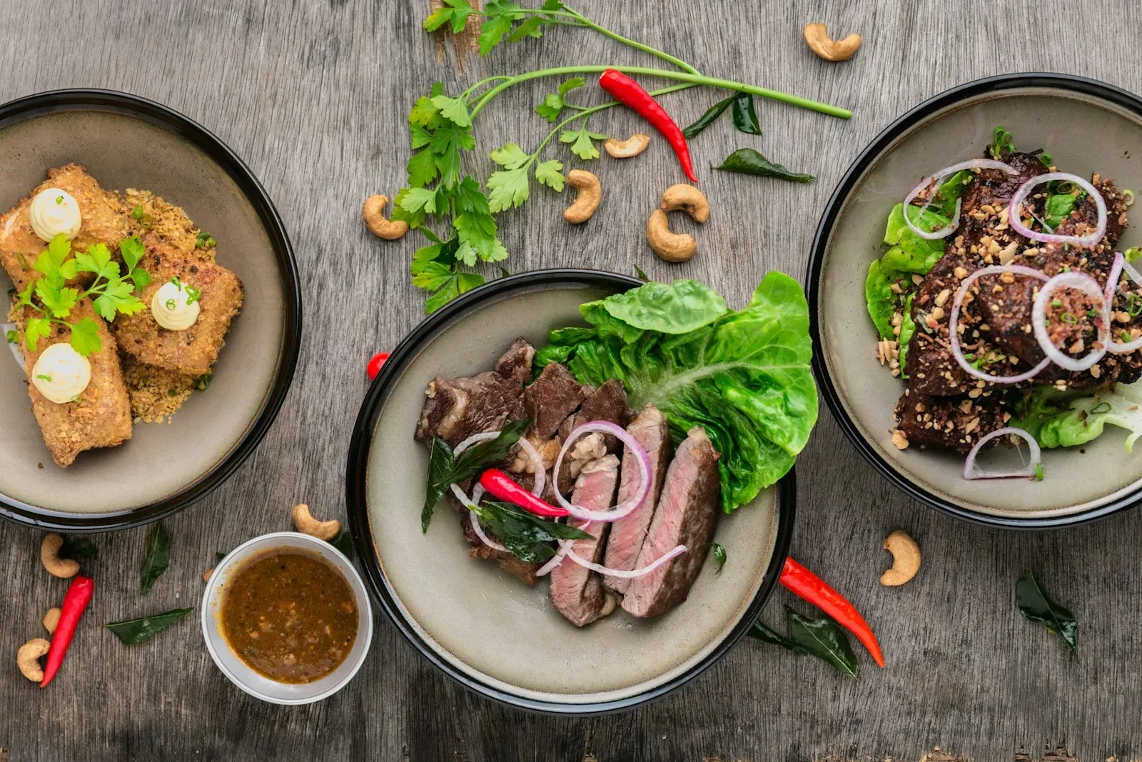 Three plated dishes and a dipping sauce photographed from above